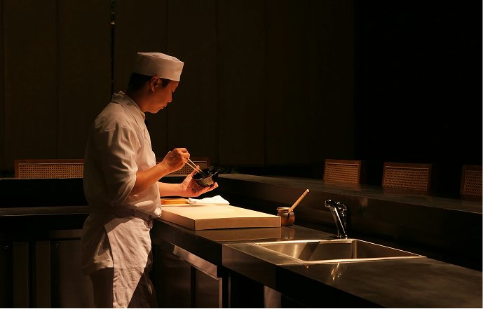 A chef plating a dish at the pass